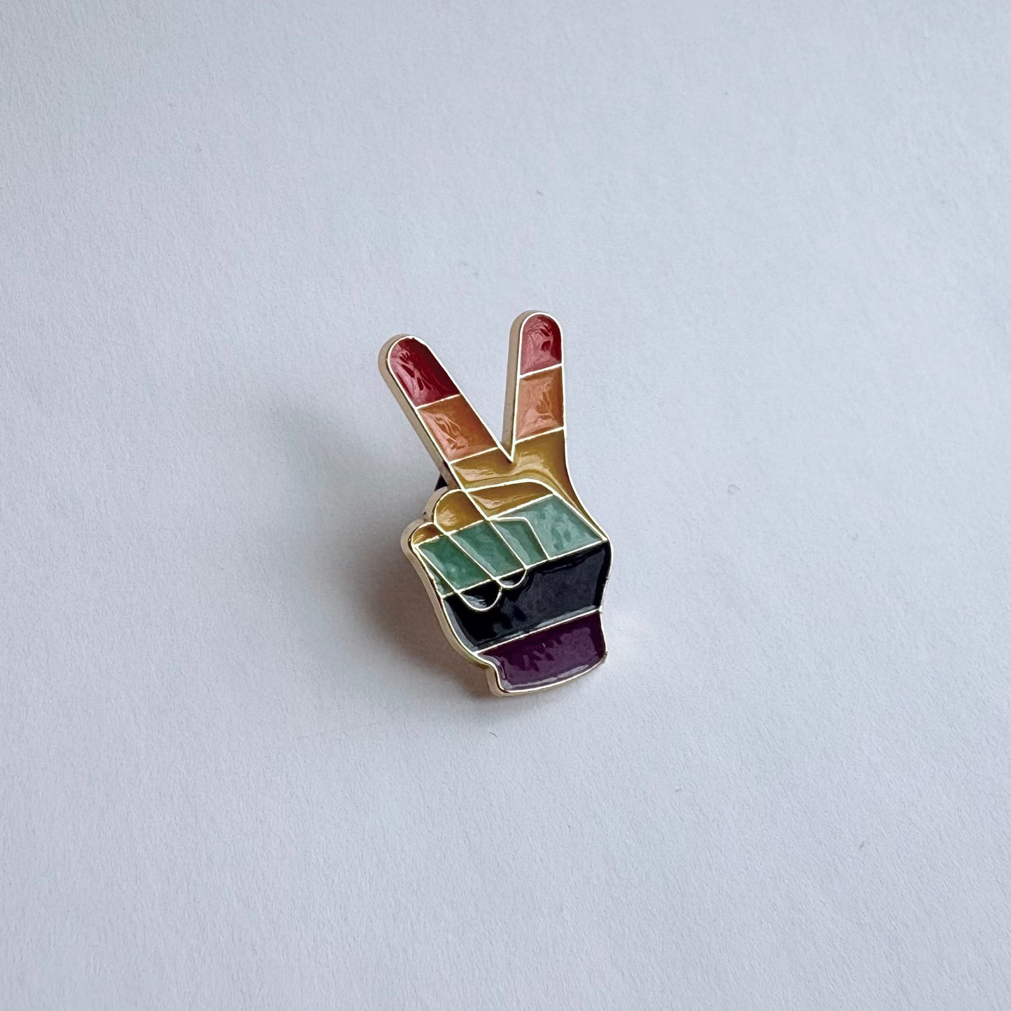 Colorful peace sign pin on a light gray background